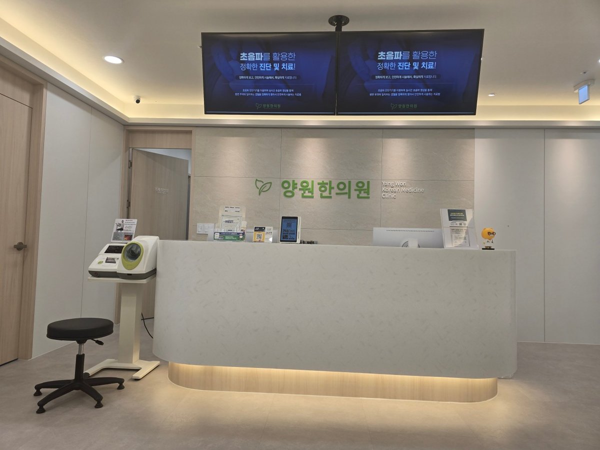 양원한의원 리셉션 — 사이니지 설치 후, 상단 삼성 디스플레이 2대에 진료시간 및 초음파 진단·치료 안내가 표시된 상태