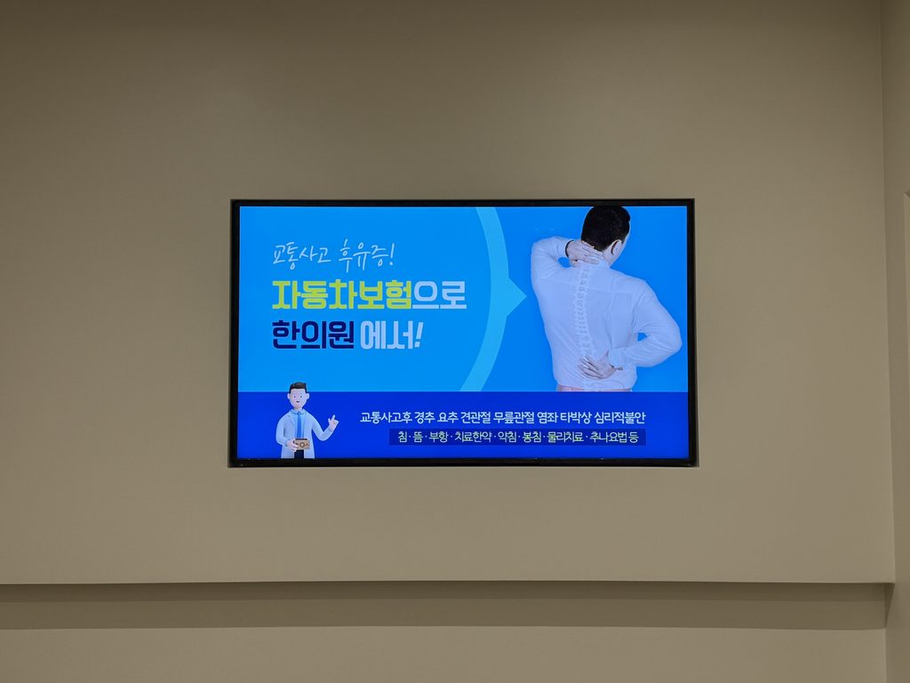 한의원 대기실 벽면의 가로형 디지털 사이니지 — 교통사고 후유증 자동차보험 한의원 치료 안내 콘텐츠 표출 화면