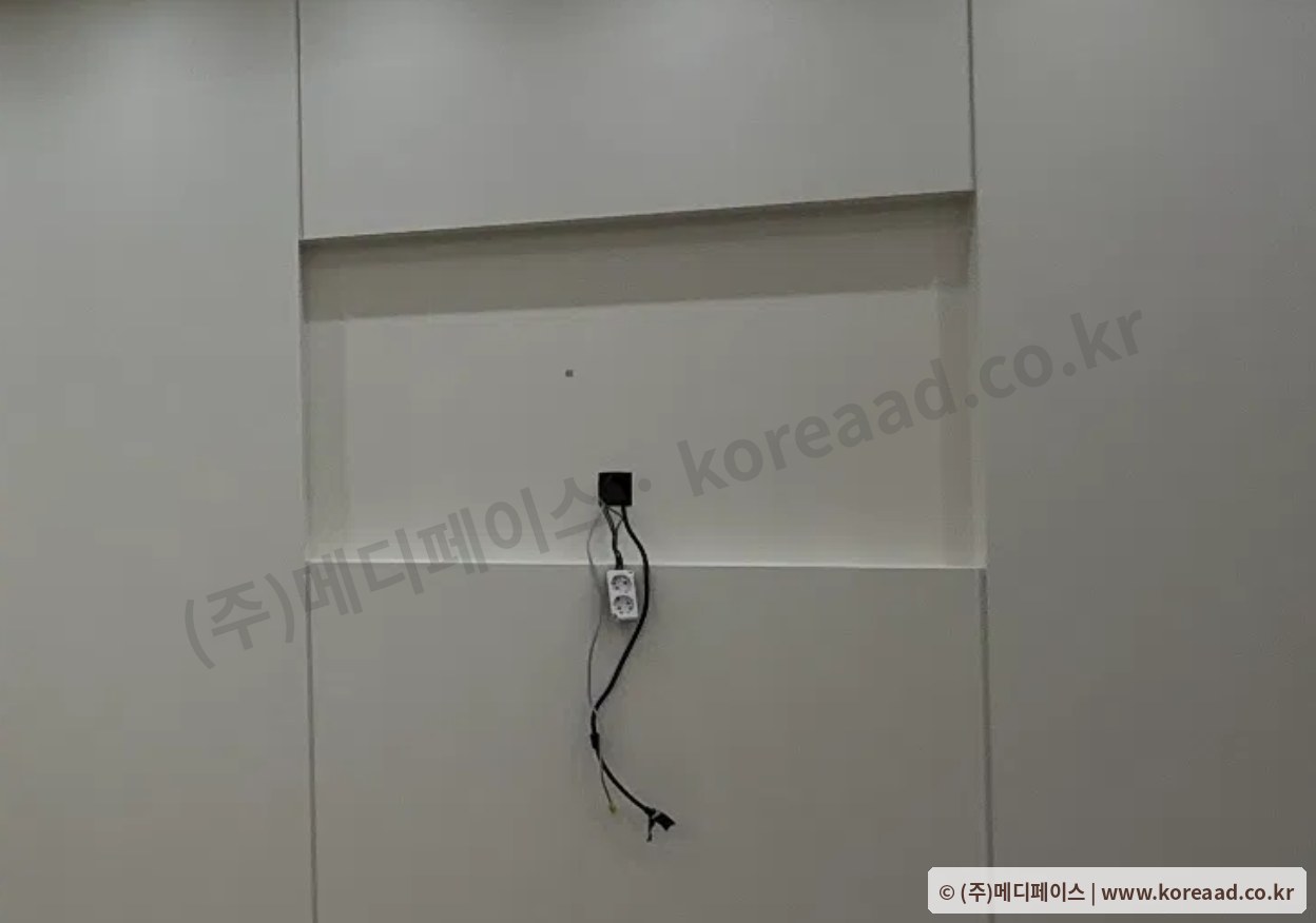 한의원 매립형 사이니지 목공 완료 현장 — 벽면에 매립틀 개구부가 만들어져 있고 내부에 전원 콘센트와 랜선이 인출되어 디스플레이 설치를 기다리는 상태