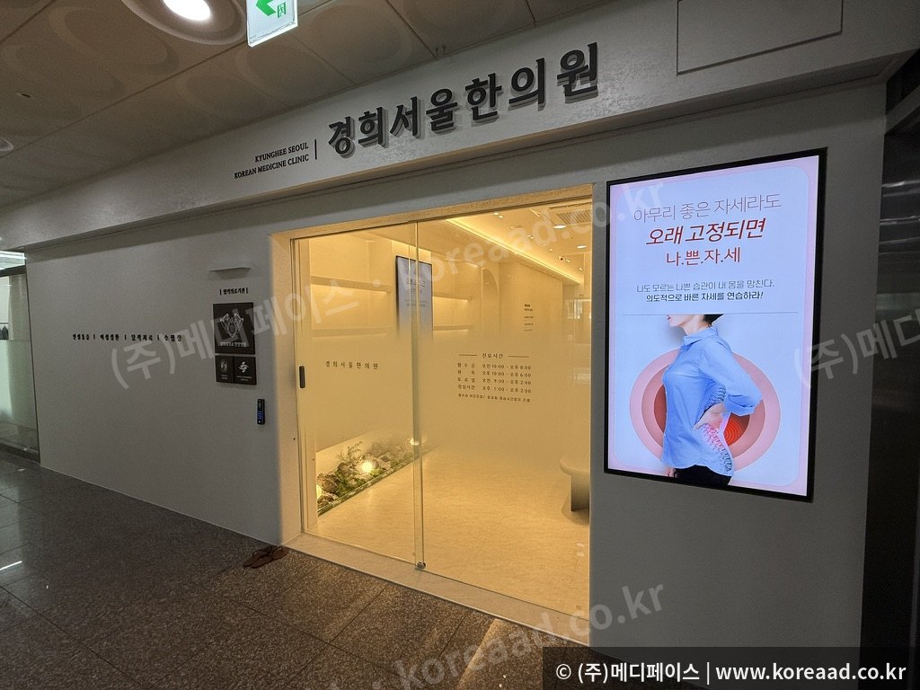 한의원 입구 세로형 사이니지 실제 설치 사진 — 바른 자세 안내 콘텐츠 표출